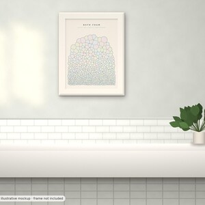 May include: A framed wall art print titled BATH FOAM featuring a graphic illustration of numerous small, multicolored bubbles arranged in a dense, rounded cluster. The artwork is displayed in a light-colored frame on a wall above a white shelf.