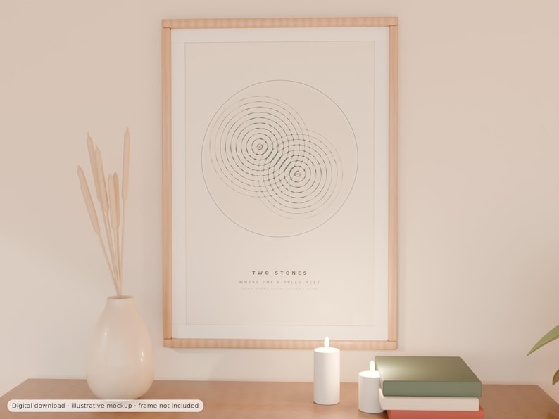 May include: A framed wall art print featuring a minimalist graphic of two overlapping circular ripple patterns. The text "TWO STONES" is printed in black below the graphic. The print is enclosed in a light-colored wooden frame.