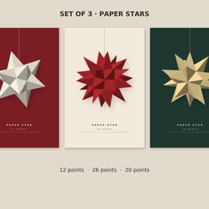 Może przedstawiać: Zestaw trzech papierowych gwiazd z napisem SET OF 3 PAPER STARS. Pierwsza to biała 12-ramienna gwiazda na czerwonym tle, druga to czerwona 26-ramienna gwiazda na kremowym tle, a trzecia to złota 20-ramienna gwiazda na ciemnozielonym tle.