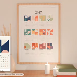 Könnte beinhalten: Ein Wandkalender für 2027 mit zwölf Monatsabschnitten, die jeweils eine einzigartige geometrische Grafik in Blau-, Orange-, Grün- und Rosatönen aufweisen. Der Kalender zeigt oben das Jahr 2027 mit den Monaten von Januar bis Dezember.
