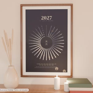 May include: A vertical wall poster titled 2027 A Year of Moons, featuring a dark gray background with a circular diagram of moon phases. The text 2027 A Year of Moons is printed at the top, with a radial arrangement of lunar cycles displayed below.