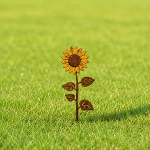 May include: A metal sunflower garden stake featuring a textured, rusted brown stem and leaves with a vibrant yellow and orange painted flower head. The sunflower has a dark brown center and detailed petals, standing upright as a decorative garden ornament.