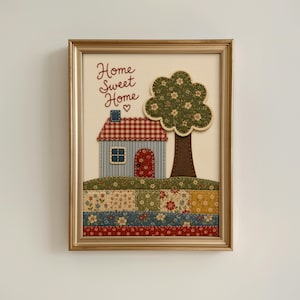 May include: A framed fabric wall art piece featuring a house with a red and white checkered roof, a blue striped wall, and a red door. Next to the house is a green tree with white flowers. The text Home Sweet Home is stitched in red thread.