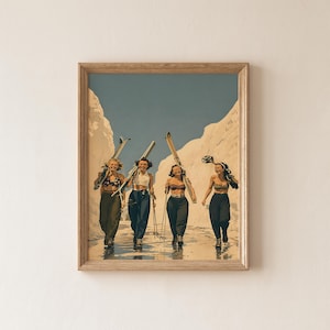 May include: A framed wall art print depicting four individuals walking through a snowy landscape, each carrying skis and poles. They are dressed in bikini tops and dark trousers, set against a backdrop of high, light-colored snow banks under a clear sky.