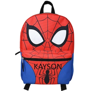 May include: A red and blue backpack featuring a large spiderweb pattern and two white eyes on the front. The front pocket displays the name KAYSON in black capital letters above a black spider graphic. It has a black top handle and black straps.