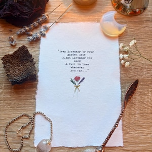 Puede incluir: Un papel rectangular blanco con bordes irregulares que presenta el texto impreso en negro: Keep Rosemary by your garden gate, Plant Lavender for Luck, & fall in love whenever you can, junto a una pequeña ilustración de un ramo.