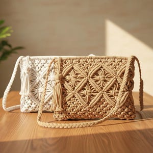Puede incluir: Dos bolsos bandolera de macramé rectangulares, uno en beige y otro en blanco, con intrincados patrones de rombos anudados y borlas a juego. Cada bolso incluye una correa trenzada para el hombro y una estructura de cordón tejido.