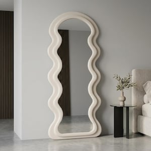 May include: A full-length floor mirror featuring a thick, cream-colored frame with a distinct wavy, organic silhouette. The mirror has an arched top and a smooth, continuous border that curves along both sides, creating a fluid, elongated shape.