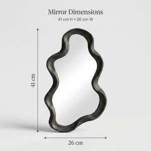 May include: An irregular, wavy-shaped mirror with a thick black frame. Text at the top reads Mirror Dimensions 41 cm H x 26 cm W. Arrows indicate the height of 41 cm and width of 26 cm, showing the mirror is approximately 16.14 inches by 10.24 inches.