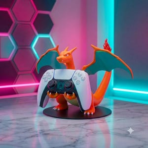 May include: A bright orange Charizard figurine standing on a circular black base, holding a white and black video game controller. The creature features teal-colored wings and a small flame at the tip of its tail, designed as a gaming accessory.