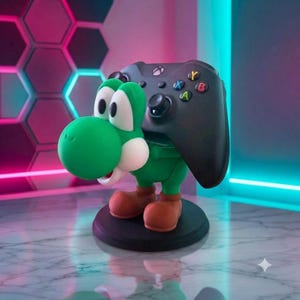 Peut inclure: Une figurine de personnage Yoshi verte et blanche servant de support de manette, tenant une manette de jeu sans fil noire avec des boutons A, B, X et Y colorés. La figurine repose sur une base noire circulaire, avec des chaussures marron.