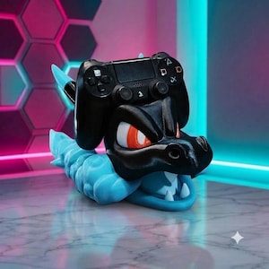 May include: A black and light blue dragon-shaped controller stand holding a black game controller. The dragon figure features a glossy black head with orange eyes, a light blue textured body, and an open mouth showing white teeth.