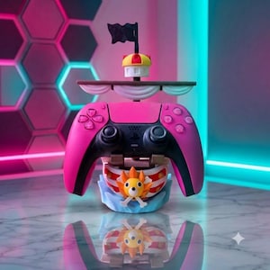 Può includere: Un controller per videogiochi rosa e nero montato su un supporto a forma di scafo di nave con una polena a forma di leone. Il supporto presenta un albero con una vela bianca, una piccola coffa gialla e rossa e una bandiera nera in cima.