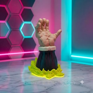 May include: A sculpted figurine featuring a beige human-like hand emerging from a dark sleeve, set atop a vibrant yellow energy aura base. The hand is positioned with fingers spread, and the base has a jagged, flame-like appearance.