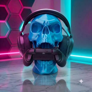Puede incluir: Una escultura de cráneo humano azul brillante que sirve como soporte para auriculares de juego negros y un mando de juego negro. El cráneo presenta un acabado liso y brillante y está colocado para sostener los auriculares en el cráneo y el mando en la mandíbula.