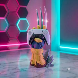 May include: A yellow and blue sculpted hand stand featuring three metallic silver claws extending upward, holding a white and black video game controller. The base of the stand is shaped like a forearm with a jagged, grey rock-like structure attached.