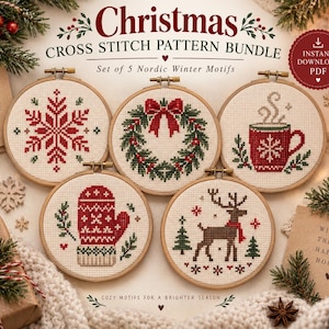 May include: A Christmas cross stitch pattern bundle featuring five Nordic winter motifs in wooden embroidery hoops. The designs include a red snowflake, a green wreath with a red bow, a red mug, a red mitten, and a brown reindeer with a red scarf.