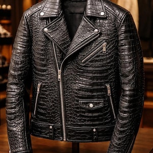 May include: A black motorcycle jacket featuring a textured crocodile skin pattern. The jacket includes a wide notched lapel, silver-toned metal zippers on the front and pockets, a small flap pocket with a snap button, and adjustable snap closures.