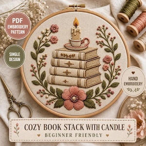 May include: An embroidery hoop containing a design of a stack of four beige books topped with a lit candle in a small cup. The stack is framed by green leafy vines and pink flowers. The text COZY BOOK STACK WITH CANDLE BEGINNER FRIENDLY is visible.