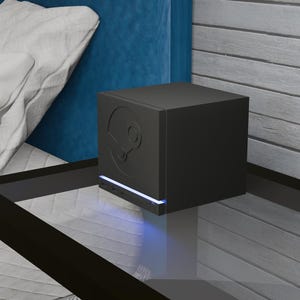 May include: A matte black, cube-shaped Steam Link streaming device featuring the embossed Steam logo on the front panel. The device includes a thin, horizontal blue LED light strip positioned near the base, which casts a soft glow onto the surface.