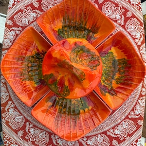 May include: A ceramic serving set featuring a central round lidded bowl surrounded by four fan-shaped dishes. The pieces are finished in a vibrant orange glaze with dark green drip accents and a ribbed texture radiating from the center.
