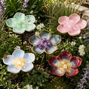 May include: Five ceramic flower-shaped garden stakes featuring glossy petals in mint green, soft pink, blue, deep red, and a central grey-blue tone. Each flower centre is filled with small, polished gemstone beads in matching or contrasting colours.