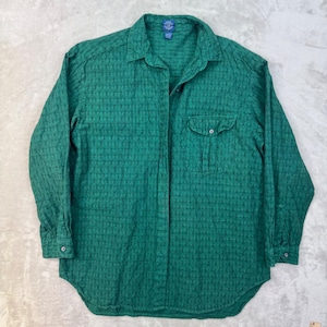 May include: A long-sleeved button-down shirt in a deep emerald green hue, featuring a subtle, repeating geometric textured pattern throughout. The shirt includes a pointed collar, a single chest pocket with a button closure, and buttoned cuffs.