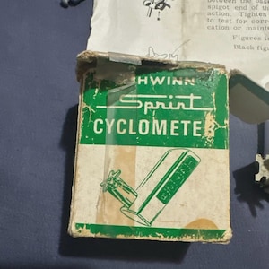 May include: A vintage Schwinn Sprint Cyclometer box featuring a green and white color scheme. The front of the box displays the text Schwinn Sprint CYCLOMETER and a line drawing of the device. The cardboard packaging shows signs of wear.