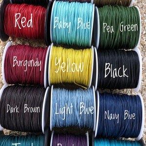 May include: A variety of colorful cotton cord spools are displayed, including grey, pink, beige, red, baby blue, pea green, burgundy, yellow, black, dark brown, light blue, navy blue, teal, purple, and turquoise. The text "Cotton Cord" is also visible.