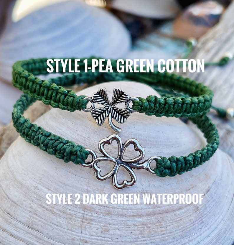 May include: Two green macrame bracelets with silver clover charms. One is pea green cotton, the other is dark green waterproof. The bracelets are displayed on a seashell. Text on the image reads "STYLE 1-PEA GREEN COTTON" and "STYLE 2 DARK GREEN WATERPROOF."