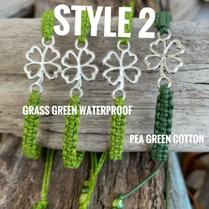 May include: Four green shamrock charms with silver-colored clover pendants. The charms are attached to green woven cords. The text "STYLE 2" is at the top. The text "GRASS GREEN WATERPROOF" and "PEA GREEN COTTON" are also visible.