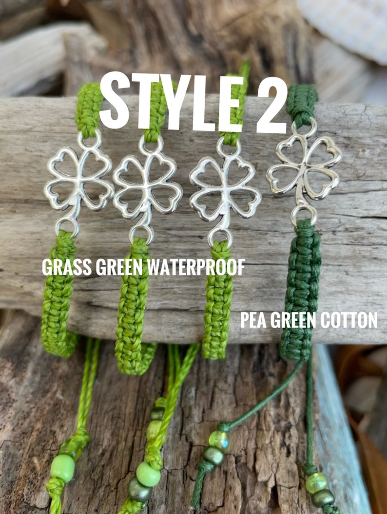 May include: Four green shamrock charms with silver-colored clover pendants. The charms are attached to green woven cords. The text "STYLE 2" is at the top. The text "GRASS GREEN WATERPROOF" and "PEA GREEN COTTON" are also visible.