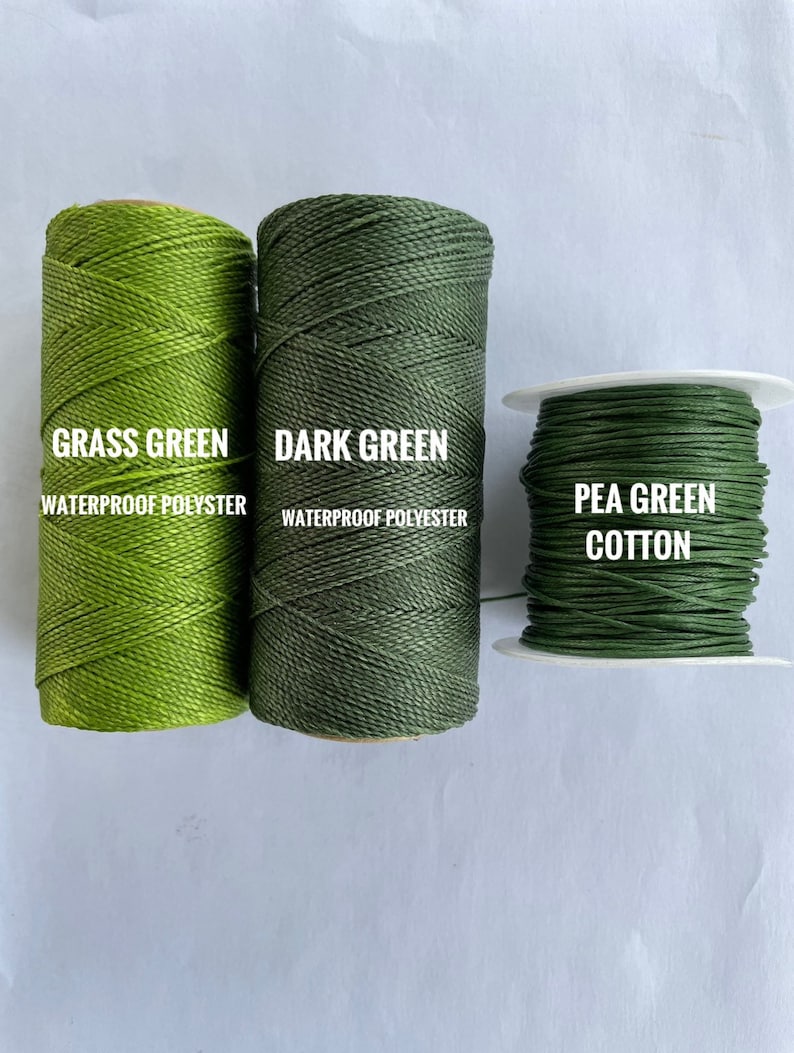 May include: Three spools of thread in varying shades of green. The left spool is grass green waterproof polyester, the middle spool is dark green waterproof polyester, and the right spool is pea green cotton.