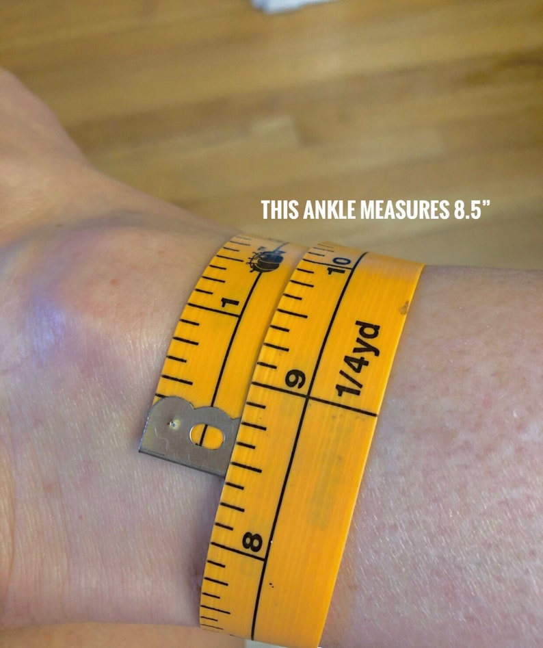 May include: A yellow measuring tape wrapped around an ankle, showing a measurement of 8.5 inches. The text "THIS ANKLE MEASURES 8.5" is visible in white.