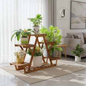 May include: A multi-tiered wooden plant stand with a folding A-frame design, featuring several shelves holding various potted plants, including a gold metallic pot, a white pot with dandelion prints, and other assorted green foliage.