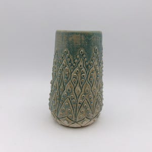 Könnte beinhalten: Eine Keramikvase mit teal-farbener Glasur und einem geprägten Muster aus Blättern und Punkten.
