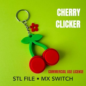 Puede incluir: Un llavero con forma de cereza que presenta dos botones circulares rojos, tallos verdes y un pequeño dije de flor roja unido a una anilla de metal plateado. El texto CHERRY CLICKER, COMMERCIAL USE LICENSE, STL FILE y MX SWITCH es visible.