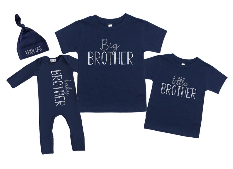 May include: A set of three navy blue clothing items for siblings. A long-sleeved baby onesie with the text "baby brother" in white, a t-shirt with the text "big brother" in white, and a t-shirt with the text "little brother" in white.