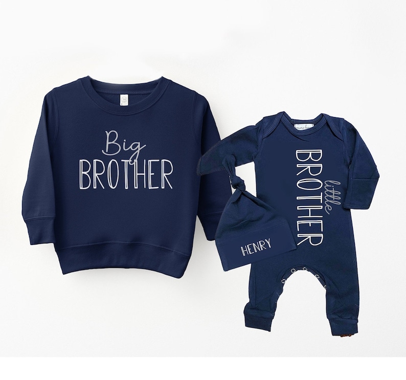 May include: A navy blue sweatshirt with the text "Big Brother" in white. A navy blue baby onesie with the text "little brother" in white. A navy blue hat with the name "Henry" in white.