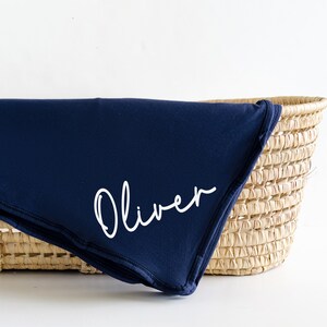 May include: A navy blue baby blanket with the name "Oliver" embroidered in white.