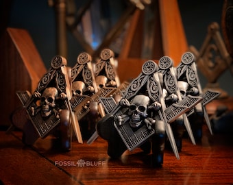 Peut inclure: Un ensemble de cinq pendentifs de compas et d'équerre maçonniques en argent et bronze, ornés de crânes et d'os croisés. Les pendentifs sont détaillés avec des sculptures complexes et présentent un motif de crâne et d'os croisés.