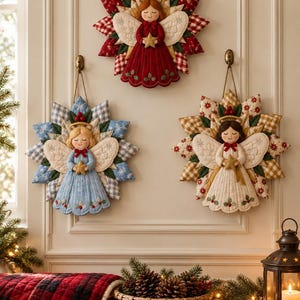 May include: Three fabric wall hangings shaped like stars, each featuring a central angel figure. The angels are dressed in red, blue, and cream, holding gold stars, with quilted wings and star-shaped backgrounds in matching colors.