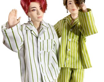May include: Two dolls with realistic facial features and styled hair. One doll has vibrant red hair and wears a white pajama shirt with vertical green stripes. The other doll has brown hair and wears a green pajama shirt with vertical white stripes.