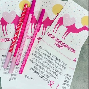 May include: A pink and white card with a cartoon camel and the text "Check Your Humps for Lumps" and "October is Breast Cancer Awareness Month". The card also includes information about breast cancer awareness and the importance of early detection.