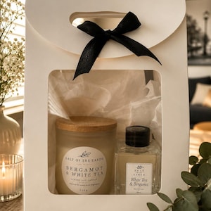 May include: A white gift box with a black ribbon handle containing a frosted glass soy candle with a wooden lid and a clear glass reed diffuser bottle. The candle label reads Salt of the Earth Bergamot & White Tea 220g, and the diffuser label reads Salt of the Earth White Tea & Bergamot.