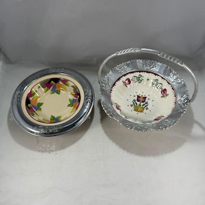 May include: Two decorative bowls. One is a round bowl with a floral design in a silver metal frame. The other is a basket-style bowl with a handle, also in silver metal, with a floral design on a white background.