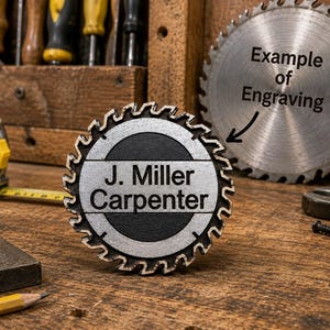 May include: A circular metal sign shaped like a saw blade with a black centre and silver teeth. The text J. Miller Carpenter is engraved in the centre. In the background, a larger saw blade features the text Example of Engraving with an arrow.