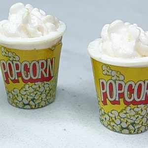 May include: Three miniature popcorn containers with white popcorn and yellow containers with red "POPCORN" text.