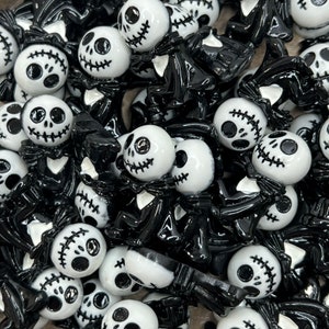May include: A collection of black and white Halloween-themed charms featuring a variety of spooky characters. The charms are made of resin and have a glossy finish.