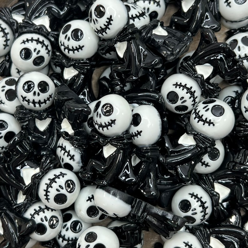 May include: A collection of black and white Halloween-themed charms featuring a variety of spooky characters. The charms are made of resin and have a glossy finish.